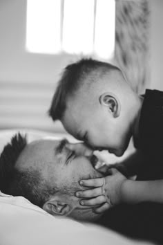 a man laying on top of a bed holding a baby