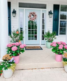 three flower pots with pink and purple flowers in front of a white house