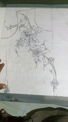 someone is holding up a piece of paper that has been drawn on it with flowers and vines