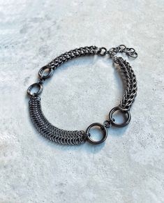 Hello! I made this DOUBLE MOON Festival Choker Necklace in Gunmetal Black Color using strong & skin-friendly, hypoallergenic aluminum rings, with the ancient craft of chainmail. * This handmade accessory will look elegant & unique on your neck. (Be ready for curious questions ;) 🎁 It would be a perfect gift for a loved one, friend or a stylish family member 🎁 - Was made with the mix of Full Persian & Byzantine chainmail patterns. - All the rings were attached to each other one by one by hand. - Clasp is stainless steel. HOW TO TAKE CARE OF YOUR ACCESSORY? * Anodized aluminum jump rings are treated with a special coating that helps protect the metal from scratches and corrosion, as well as giving them a vibrant color. However, even with this coating, the metal can still be prone to scratc Black Stainless Steel Chainmail Jewelry, Adjustable Black Chainmail Jewelry, Stainless Steel Chain Link Jewelry With Jump Ring, Gothic Gunmetal Jewelry With Chain, Gothic Gunmetal Chain Jewelry, Black Metal Chainmail Necklace, Gothic Chainmail Metal Jewelry, Handmade Metal Chain Bracelet, Gothic Stainless Steel Chainmail Jewelry