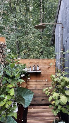 an outdoor shower in the middle of some trees and plants next to a wooden bench