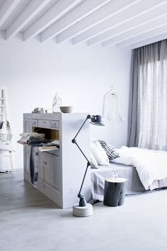 an instagramted photo of a bedroom with white walls and furniture, including a bed