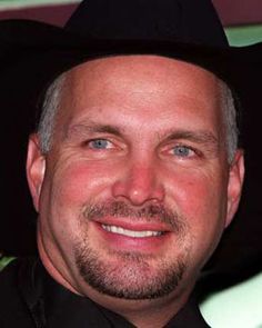 a man wearing a black hat smiling at the camera