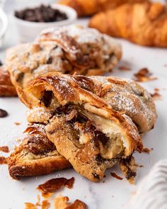 some croissants are sitting on a table with chocolate chips and powdered sugar