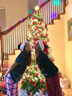 two girls standing in front of a christmas tree