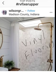 a white bathroom with black writing on the wall and a shower head in the corner