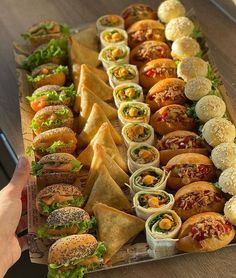 a tray filled with lots of different types of sandwiches and wraps on top of each other