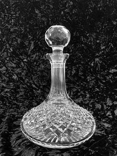 a glass decanter sitting on top of a black table next to a wall