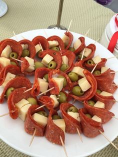 an appetizer platter with olives, cheese and meat on skewers