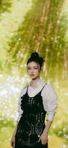 a woman standing in front of a painting wearing black overalls and a white shirt