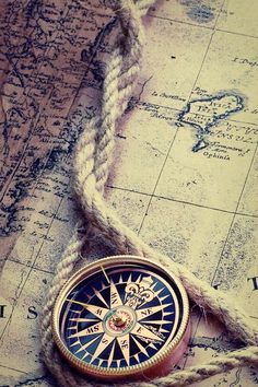 a compass and rope on top of an old map