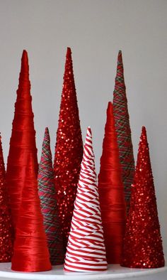 red and silver christmas trees are on a white shelf with glittery decorations around them