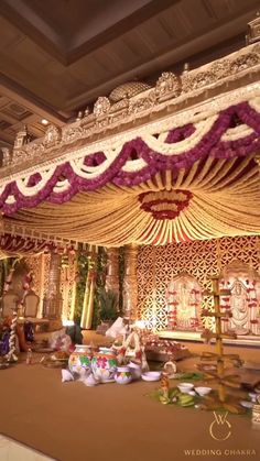 an elaborate stage set up for a wedding ceremony with flowers and decorations on the ceiling