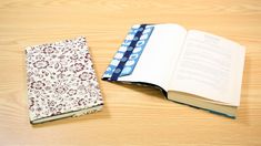 an open book sitting on top of a wooden table next to a notebook and pen