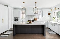 a large kitchen with white cabinets and black counter tops, along with striped flooring