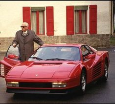 a man standing next to a red sports car