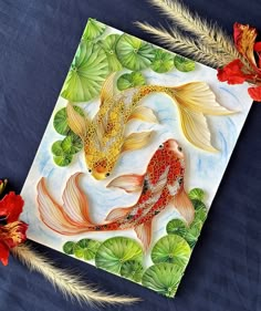 two goldfishs in water surrounded by leaves and flowers on a blue cloth background