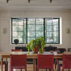 a dining room table with red chairs and a potted plant in the center on top