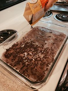 someone is pouring milk on top of a brownie in a glass baking dish with chocolate chips