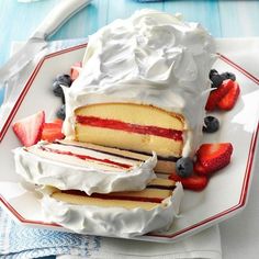 a piece of cake on a plate with strawberries and blueberries