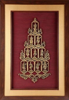 an ornate gold christmas tree framed in a wooden frame on a red wall with other ornaments