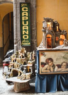 there is a painting on display next to a small table with an angel statue in it