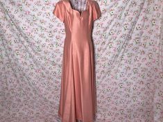 Unique vintage late 70s - early 80s  dress . Gorgeous coral pink satin material with a unique texture, v neckline, short sleeves, shoulder pads, back zipper closure, fully lined, and a maxi length hem. Would best fit a S - M, but please see the measurements to ensure a perfect fit. Original size and brand are unknown, and material is a rayon and acetate blend.Some discoloration at the bottom of the hem and a stain on the lining, please see the photos. Here to help if you have any questions.  16 in chest 14.5 in waist    20 in hips 54 in length laid flat, please double where needed Formal Pink Short Sleeve Maxi Dress, Elegant Peach Maxi Dress With Short Sleeves, Elegant Peach Short Sleeve Maxi Dress, Fitted Peach Maxi Dress With Short Sleeves, Vintage Dress 80s, 80s Dress, Satin Material, Dress Maxi, Pink Satin