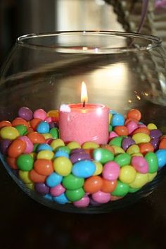 a glass bowl filled with candy and a lit candle