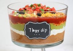 there is a layered dessert in a glass dish with a chalkboard on the top