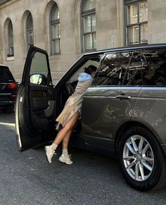 a woman leaning out the back door of a car with her legs in the open