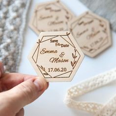 a person holding up some wooden save the date magnets on top of a table