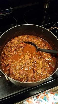 a pot filled with chili and beans on top of an open stovetop burner