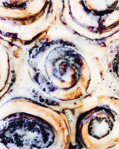 several cinnamon rolls with icing sitting on top of each other in a baking pan