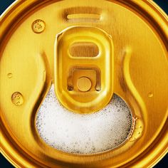 an empty gold can with water droplets on the bottom, and some bubbles in the bottom