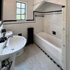 a white bathroom with black and white tile on the floor, sink and bathtub