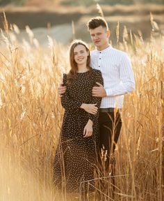 a man and woman are standing in the tall grass with their arms around each other