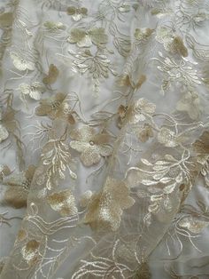 the fabric is white with gold flowers and leaves on it's side, as well as an intricate design