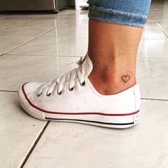 a woman's foot with a heart tattoo on it