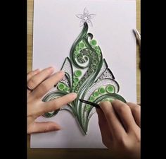 someone is drawing a christmas tree with green and white swirls on the paper,