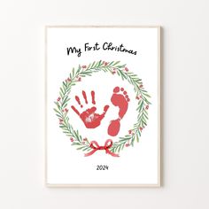 a christmas card with a hand and foot print in the center, surrounded by greenery