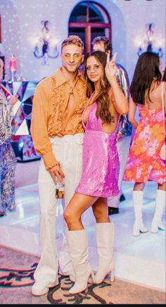 a man and woman standing next to each other in front of a disco ball backdrop