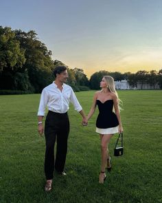 a man and woman holding hands walking across a field