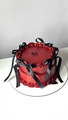 a red cake sitting on top of a white plate with black ribbon around the edges