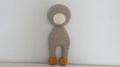 a crocheted stuffed animal is posed against a white wall