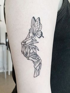 a black and white photo of a woman's arm with a butterfly tattoo on it