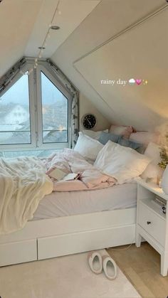 there is a bed with white sheets and pillows in the corner of this room, next to a large window