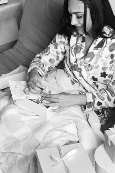 a woman sitting on a couch wrapped in a blanket and wrapping her presents for the holiday season