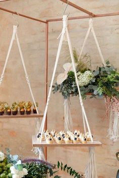 the desserts are arranged on two tiered trays with flowers and greenery