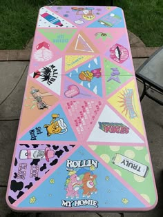 a table with many stickers on it sitting in front of a chair and some grass