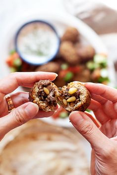 two hands holding food in front of a plate